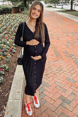 smiling pregnant woman in black ribbed button-down midi dress standing on a brick walkway outdoors