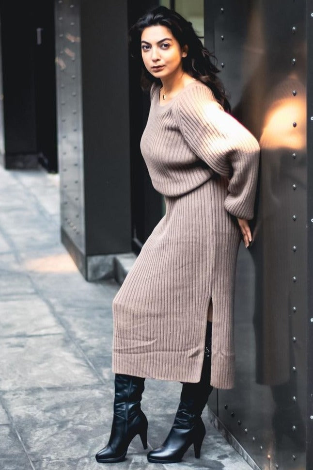 woman wearing a taupe ribbed knit midi dress with side slits and black knee-high boots
