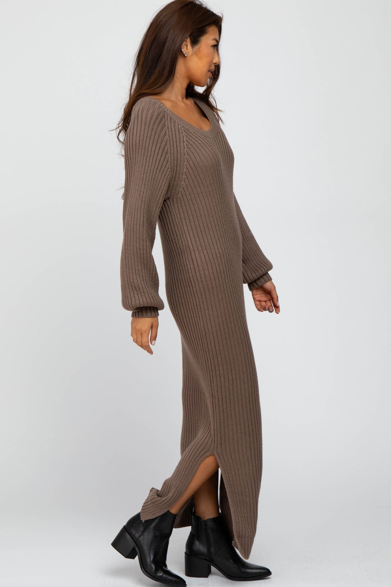 woman wearing a long brown ribbed sweater dress with side slits and long sleeves, paired with black ankle boots