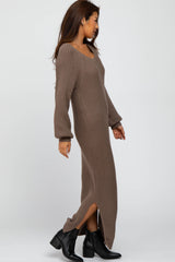 woman wearing a long brown ribbed sweater dress with side slits and long sleeves, paired with black ankle boots