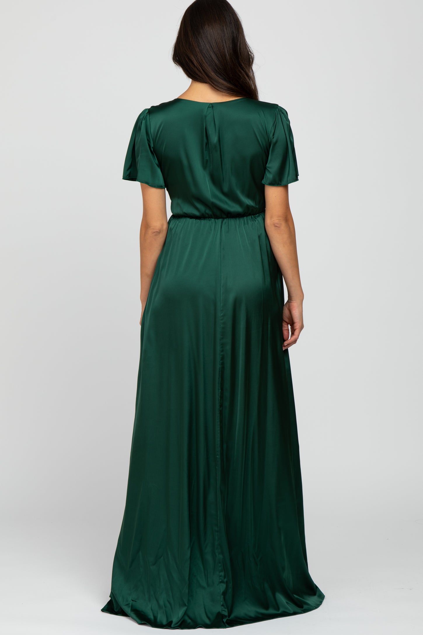 woman wearing a long green satin maxi dress with short sleeves and a cinched waist, viewed from the back