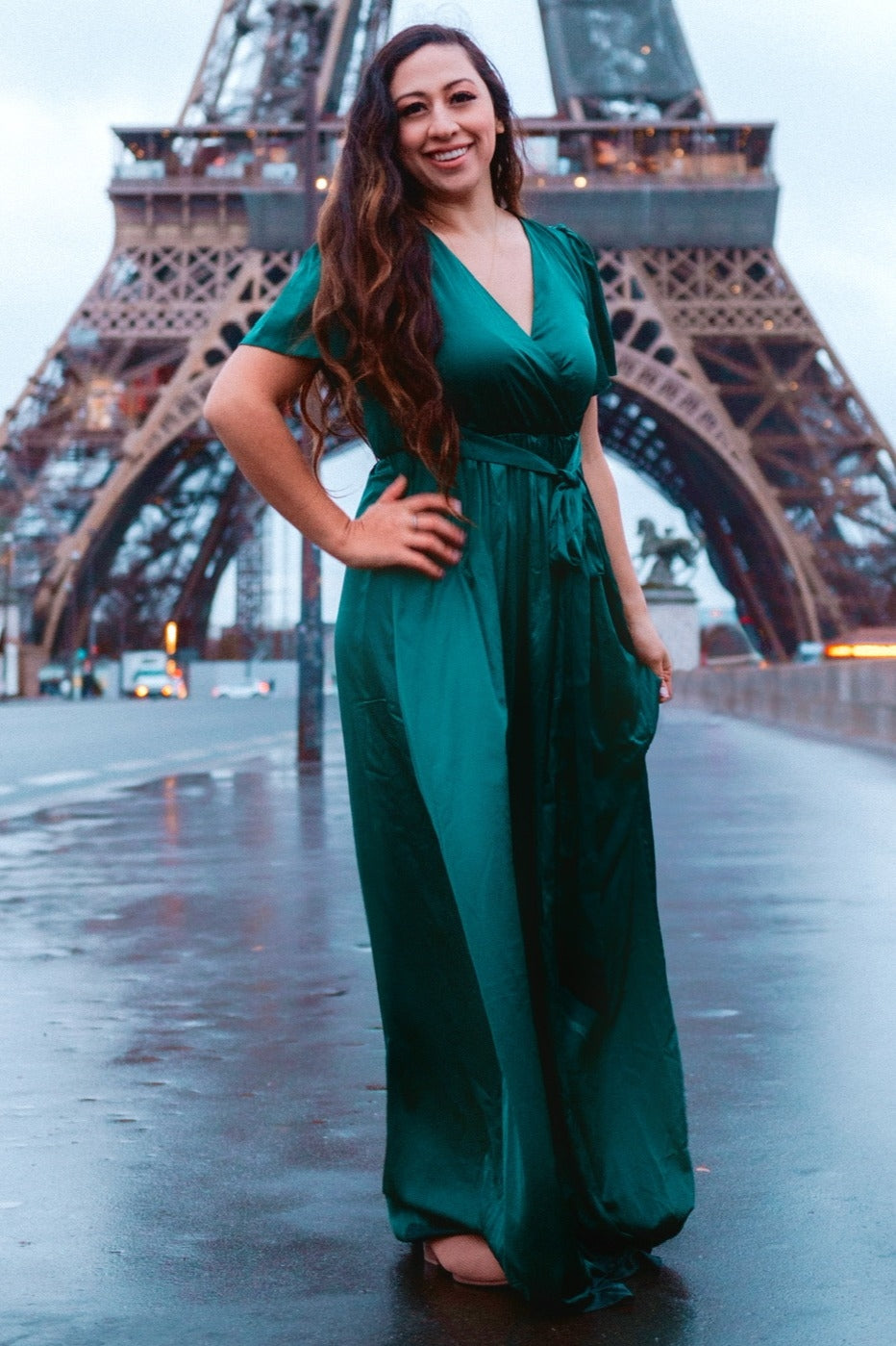 woman wearing a green satin wrap maxi dress standing in front of the eiffel tower