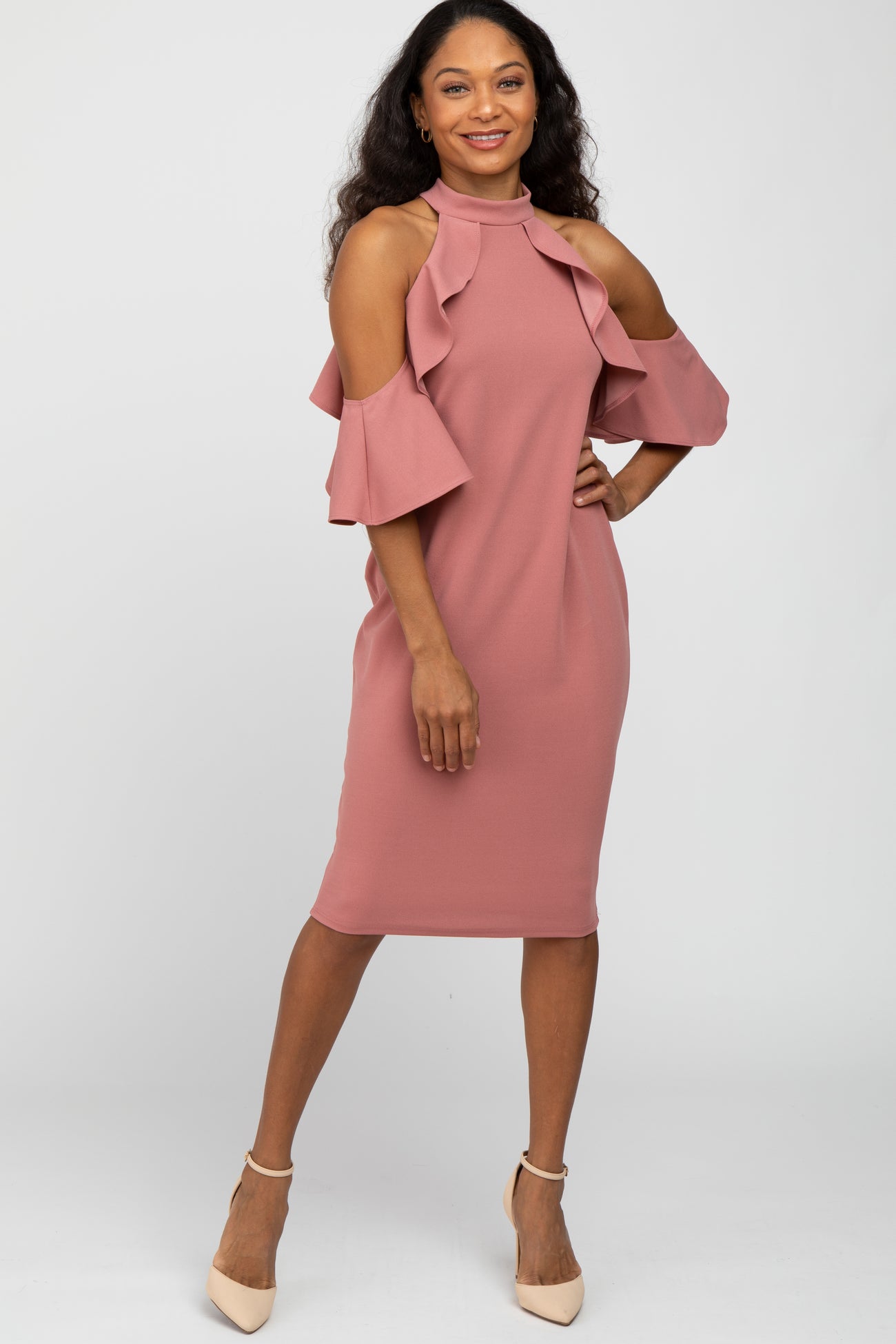 woman wearing a mauve cold shoulder ruffle dress with high neck and beige heels