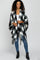 woman wearing black and white buffalo plaid poncho with fringe hem over blue jeans and black boots
