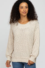 woman with curly hair wearing a cream textured knit sweater and blue jeans