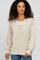 woman with curly hair wearing a cream textured knit sweater and blue jeans