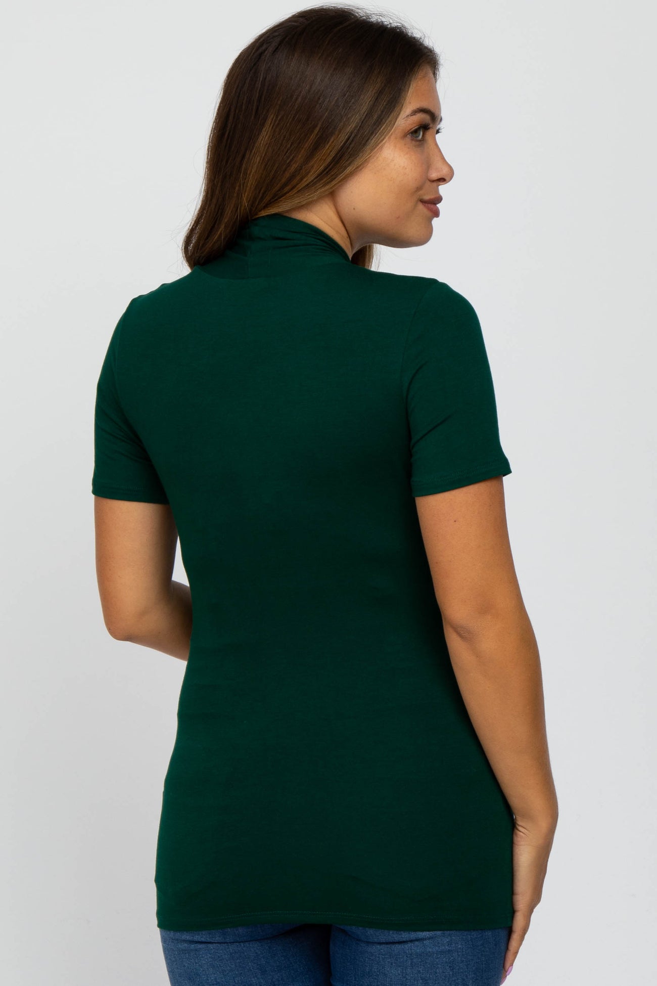 woman wearing a dark green maternity top with short sleeves and a fitted style, showing a side view