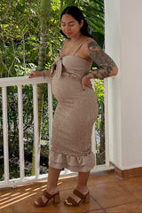woman wearing a beige maternity dress with a tie front and ruffle hem, showing her baby bump while standing outdoors