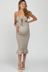 woman wearing a beige maternity dress with a knot front and ruffled hem, highlighting her baby bump