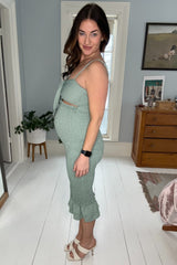 woman wearing a light green maternity dress with a knot front and ruffle hem, showcasing her baby bump
