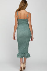 woman wearing a green smocked maternity dress with a ruffled hem and adjustable spaghetti straps, showing her back