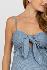 woman wearing a blue checkered maternity crop top with a front tie and spaghetti straps