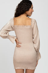 woman wearing a beige smocked mini dress with long satin sleeves and a square neckline, viewed from the back