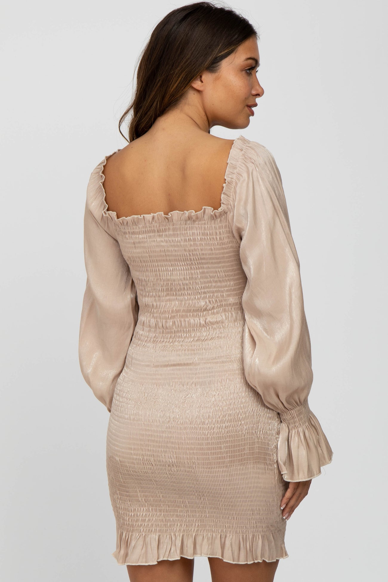woman wearing a champagne smocked bodycon dress with long puff sleeves and a square neckline