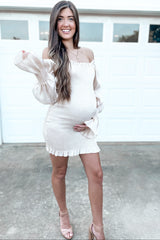 woman wearing a cream off-shoulder maternity dress with ruffled hem and long puff sleeves, holding her baby bump