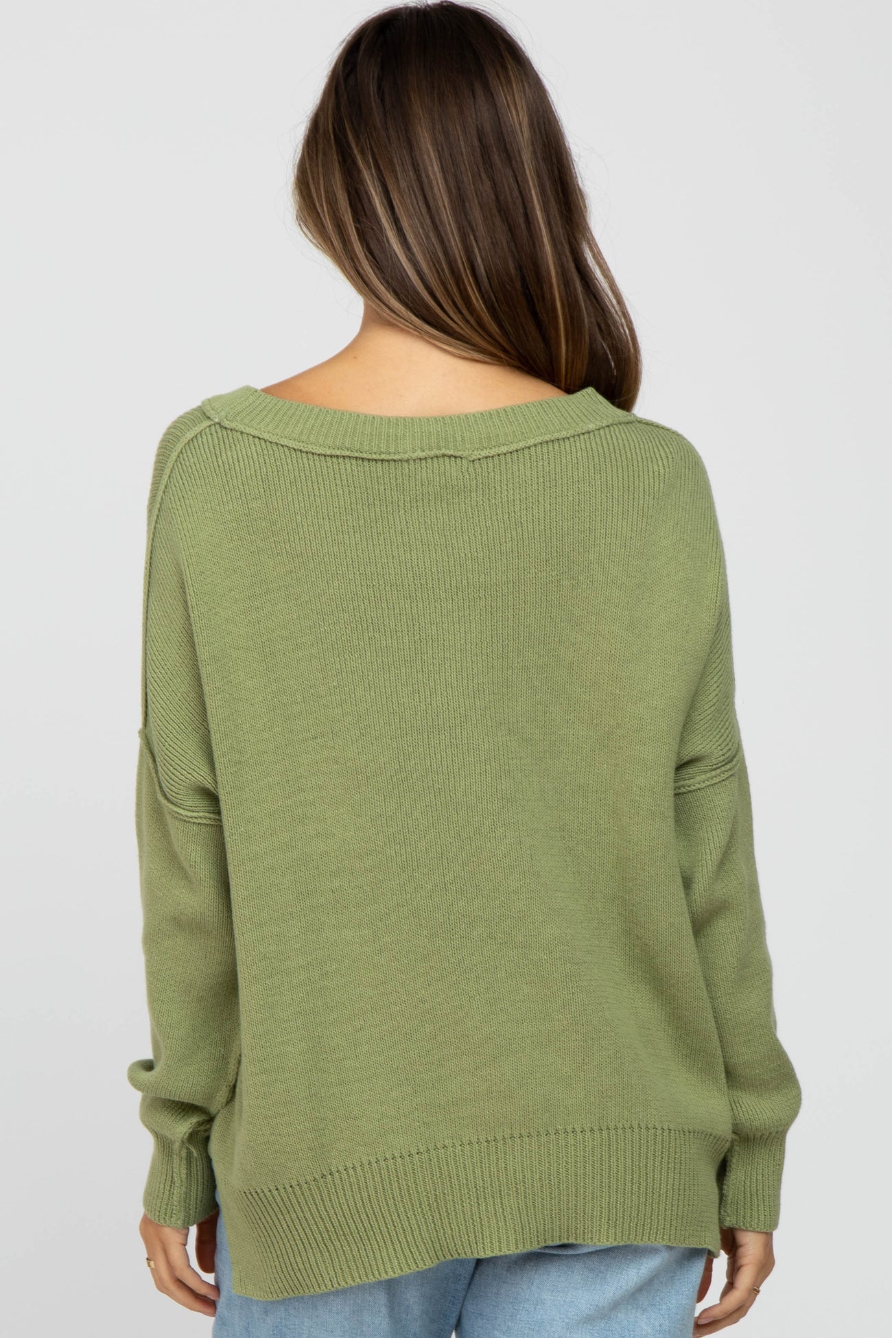 woman wearing a loose-fitting olive green maternity sweater, shown from the back