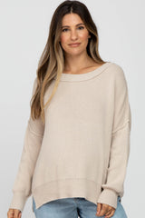 woman wearing a beige oversized knit maternity sweater with a relaxed fit and wide neckline