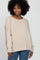 woman wearing a beige oversized sweater with a wide neckline and relaxed fit, paired with blue jeans
