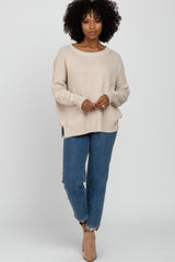 woman wearing a beige oversized knit sweater and blue high-waisted jeans, accessorized with beige ankle boots