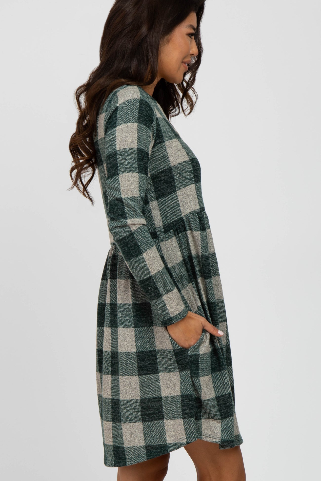 woman wearing a green and beige plaid long sleeve dress with a cinched waist and pockets