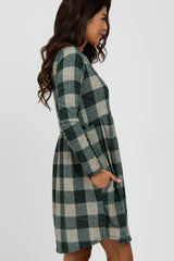 woman wearing a green and beige plaid long sleeve dress with a cinched waist and pockets