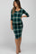 woman wearing a green plaid maternity dress with three-quarter sleeves and a visible baby bump
