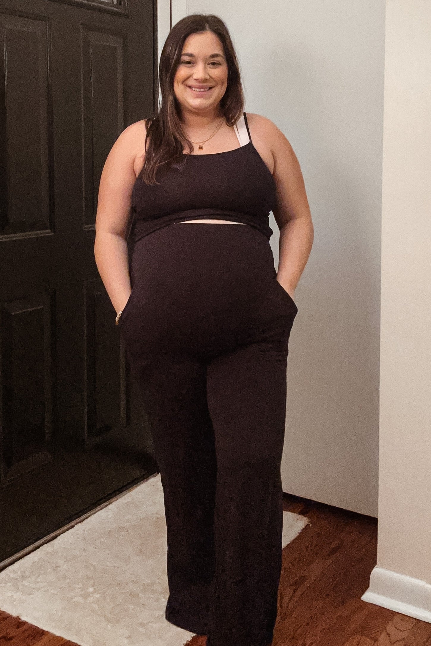 woman wearing a black maternity loungewear set with a fitted top and wide-leg pants, showing her baby bump