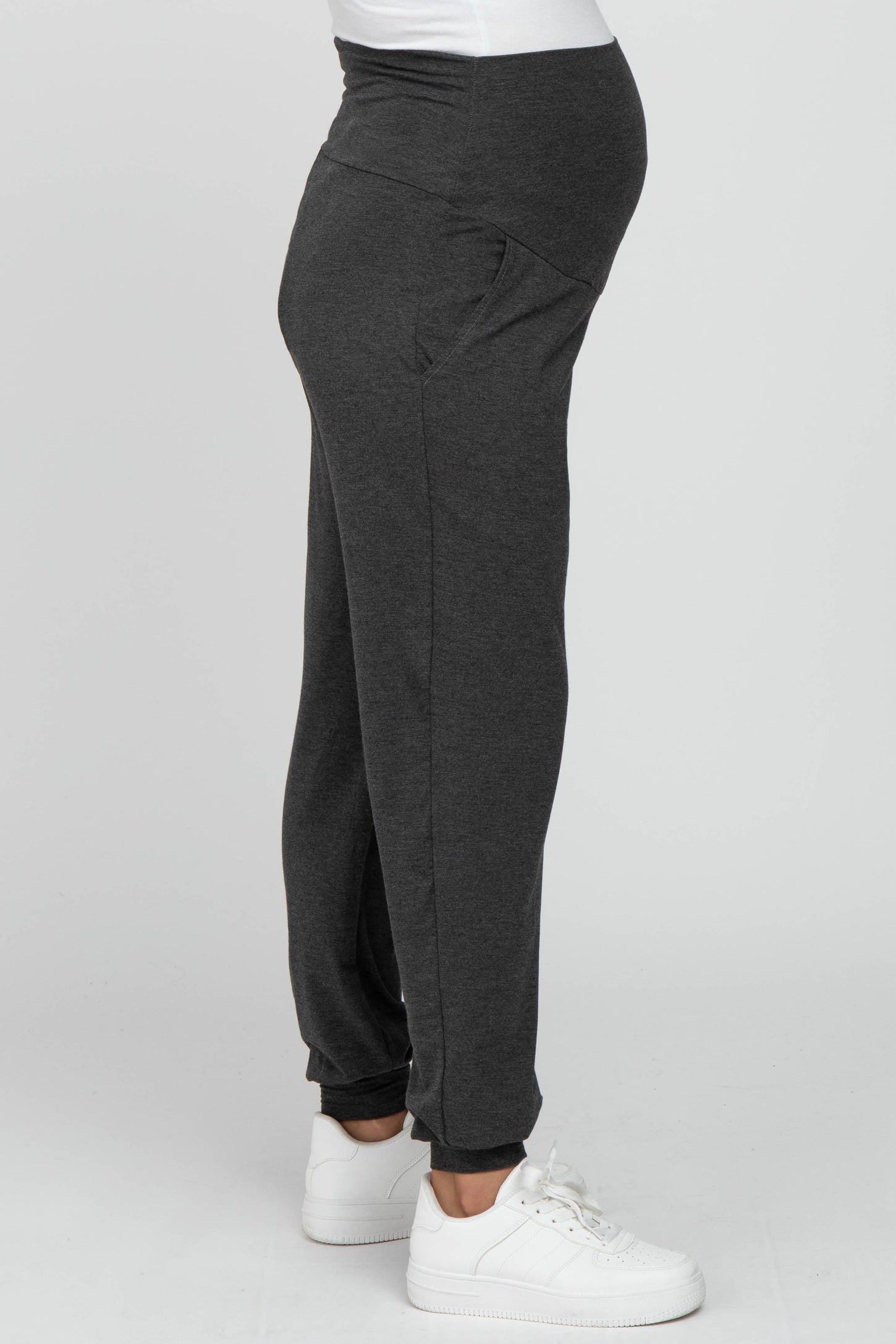 woman wearing gray maternity joggers with a waistband designed for a baby bump