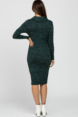 woman wearing a dark green maternity dress with a cowl neck and long sleeves, showing a baby bump from the back