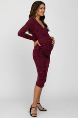woman wearing a burgundy long sleeve fitted maternity dress and holding her baby bump