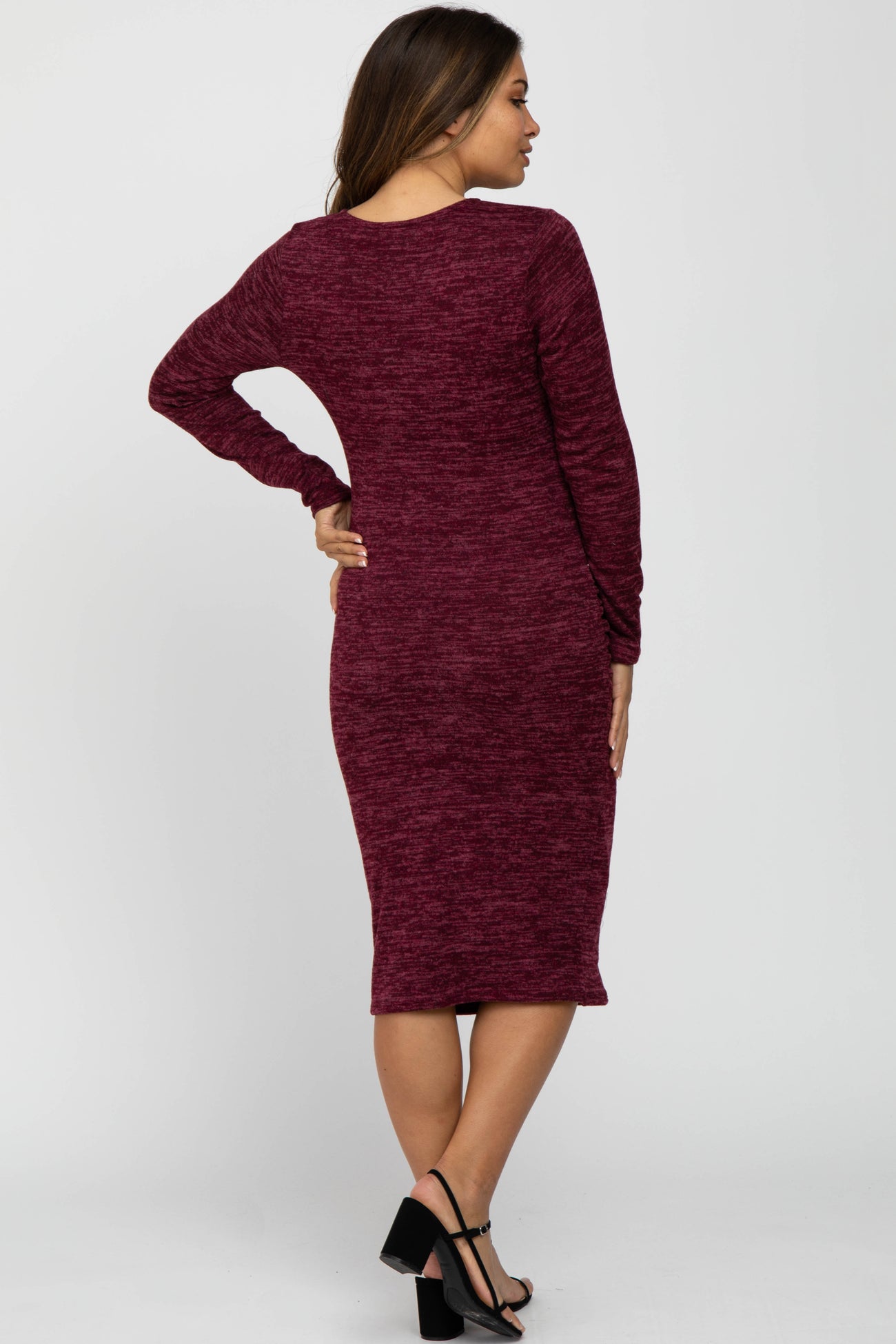 woman wearing a burgundy long sleeve maternity dress, showing a fitted silhouette and knee-length style from the back