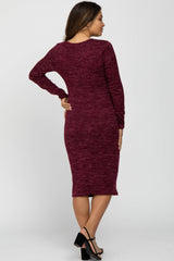woman wearing a burgundy long sleeve maternity dress, showing a fitted silhouette and knee-length style from the back