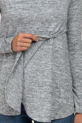 woman wearing a gray long sleeve top with a draped front detail, paired with blue jeans