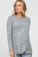 blonde woman wearing a grey long sleeve marled knit top and light wash jeans