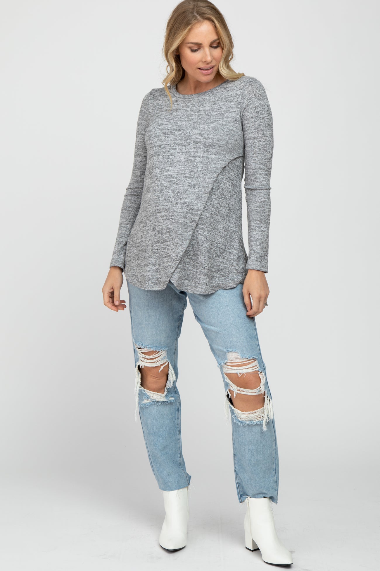 woman wearing a gray maternity long sleeve top with a crossover front and distressed light blue jeans