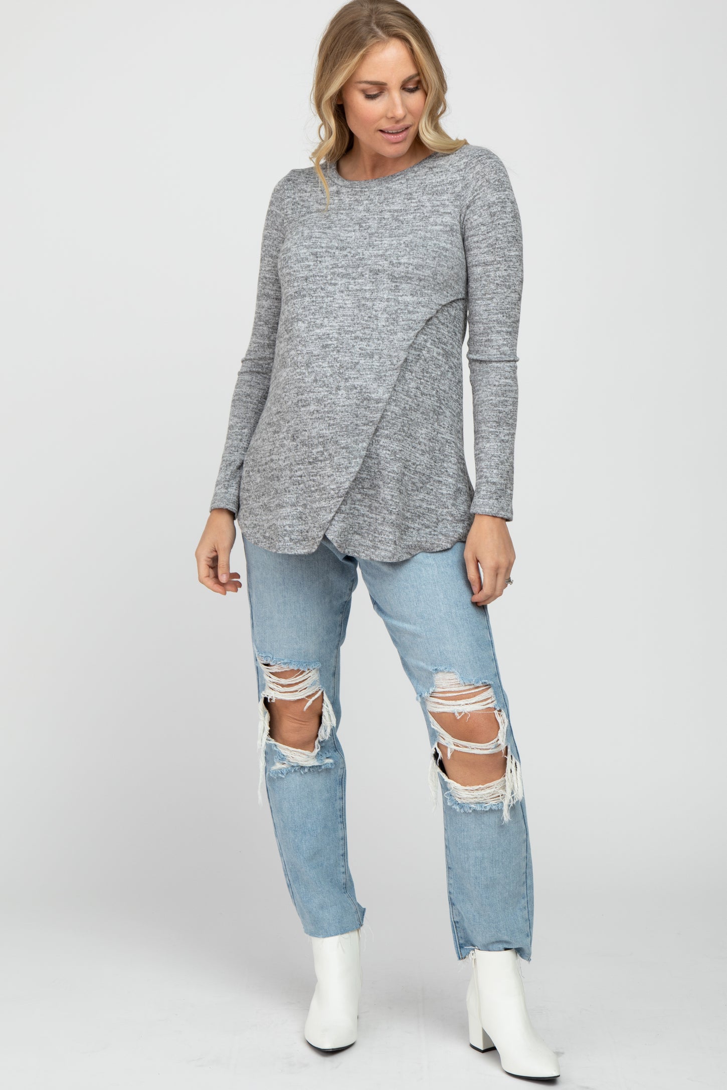 woman wearing a gray maternity long sleeve top with a crossover front and distressed light blue jeans