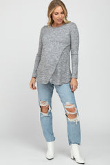 woman wearing a gray maternity long sleeve top with a crossover front and distressed light blue jeans
