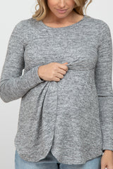 woman wearing a gray long sleeve maternity top with a knotted front detail and holding her baby bump.