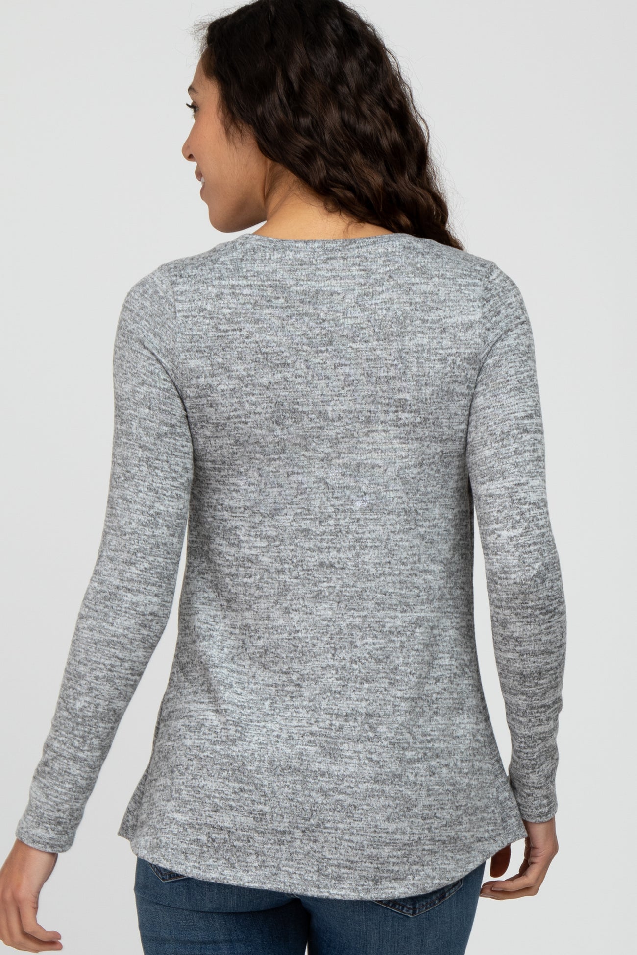 woman wearing a gray long sleeve sweater with a slightly curved hem and a relaxed fit, viewed from the back