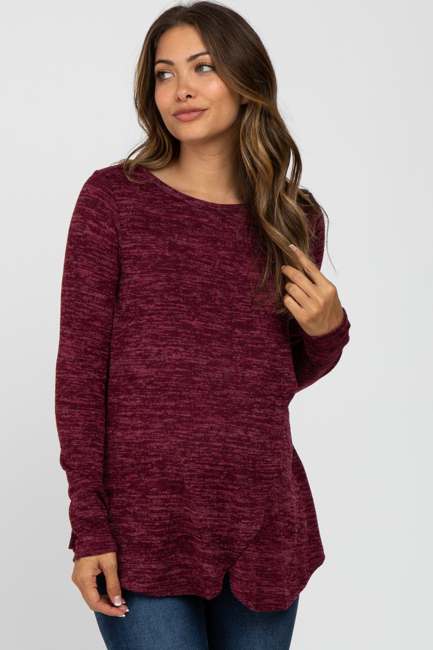woman wearing a burgundy long sleeve maternity top with a scoop neckline and side slits, styled with jeans