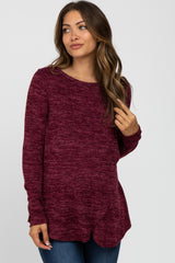 woman wearing a burgundy long sleeve maternity top with a scoop neckline and side slits, styled with jeans