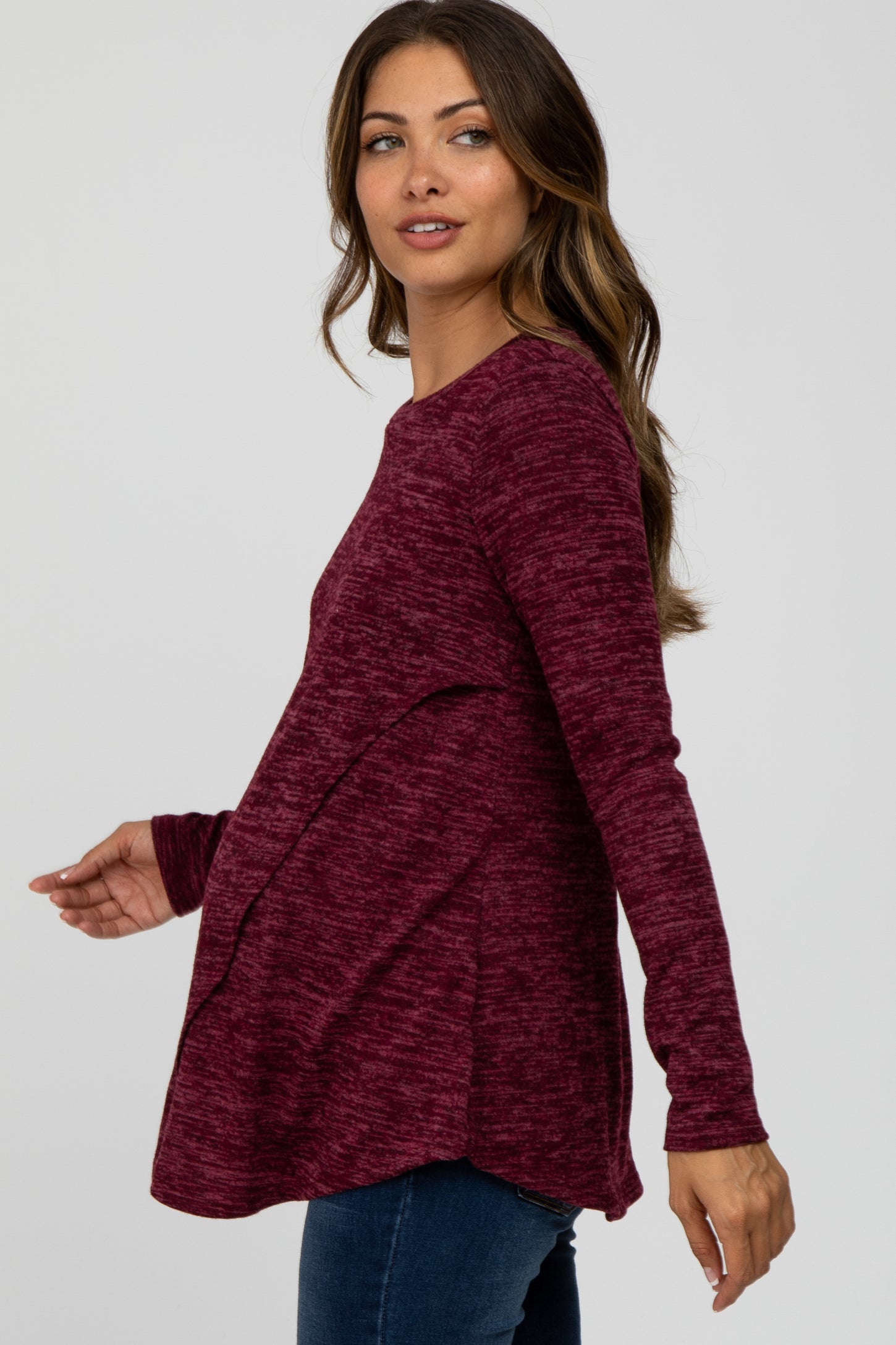 woman wearing a burgundy long sleeve maternity top with textured fabric and a relaxed fit, showcasing her baby bump