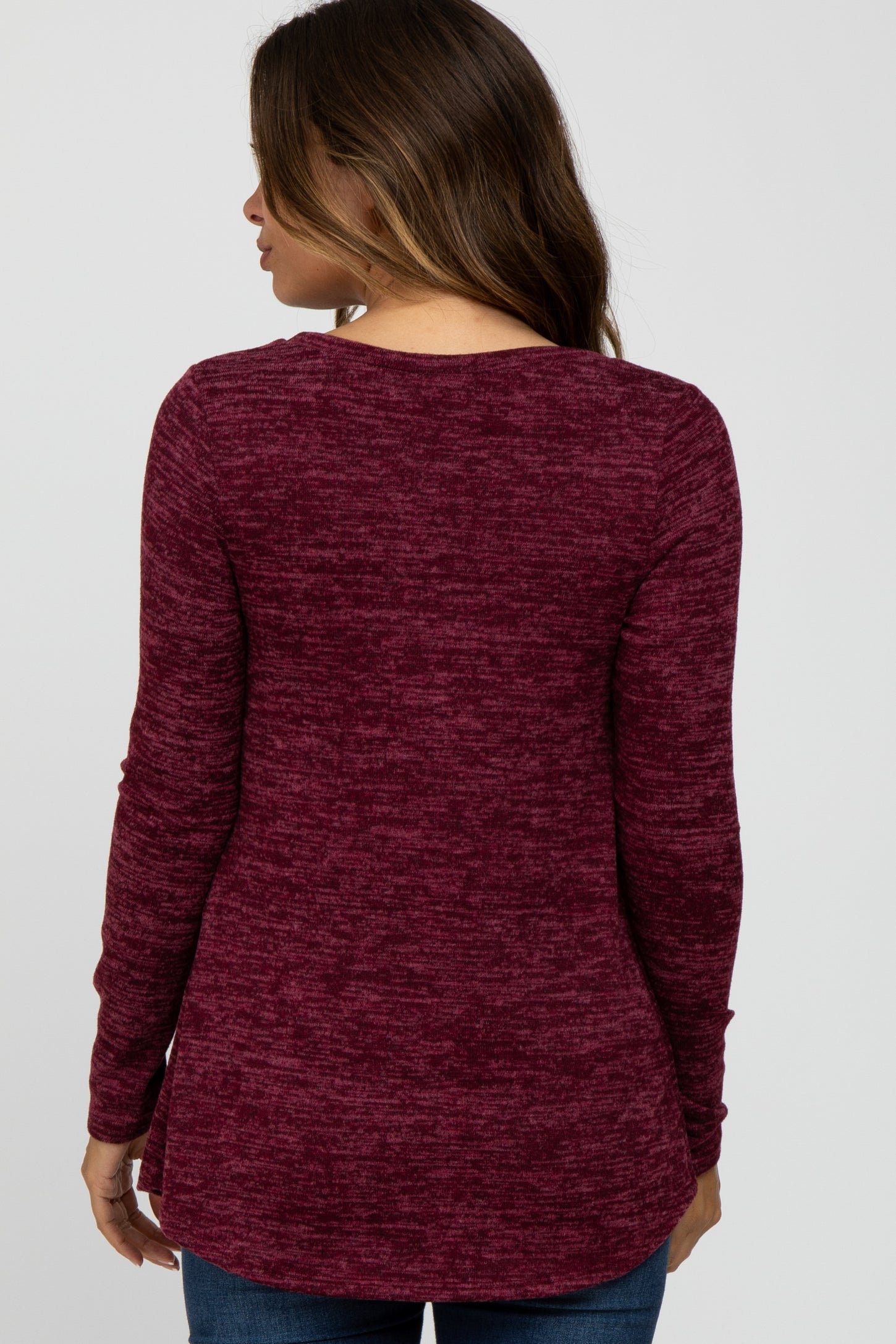 Back view of a woman wearing a long sleeve burgundy marled knit top with a scoop neckline