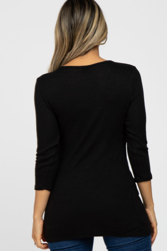 woman wearing a black long sleeve tunic top viewed from the back, paired with blue jeans