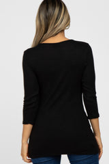 woman wearing a black long sleeve tunic top viewed from the back, paired with blue jeans