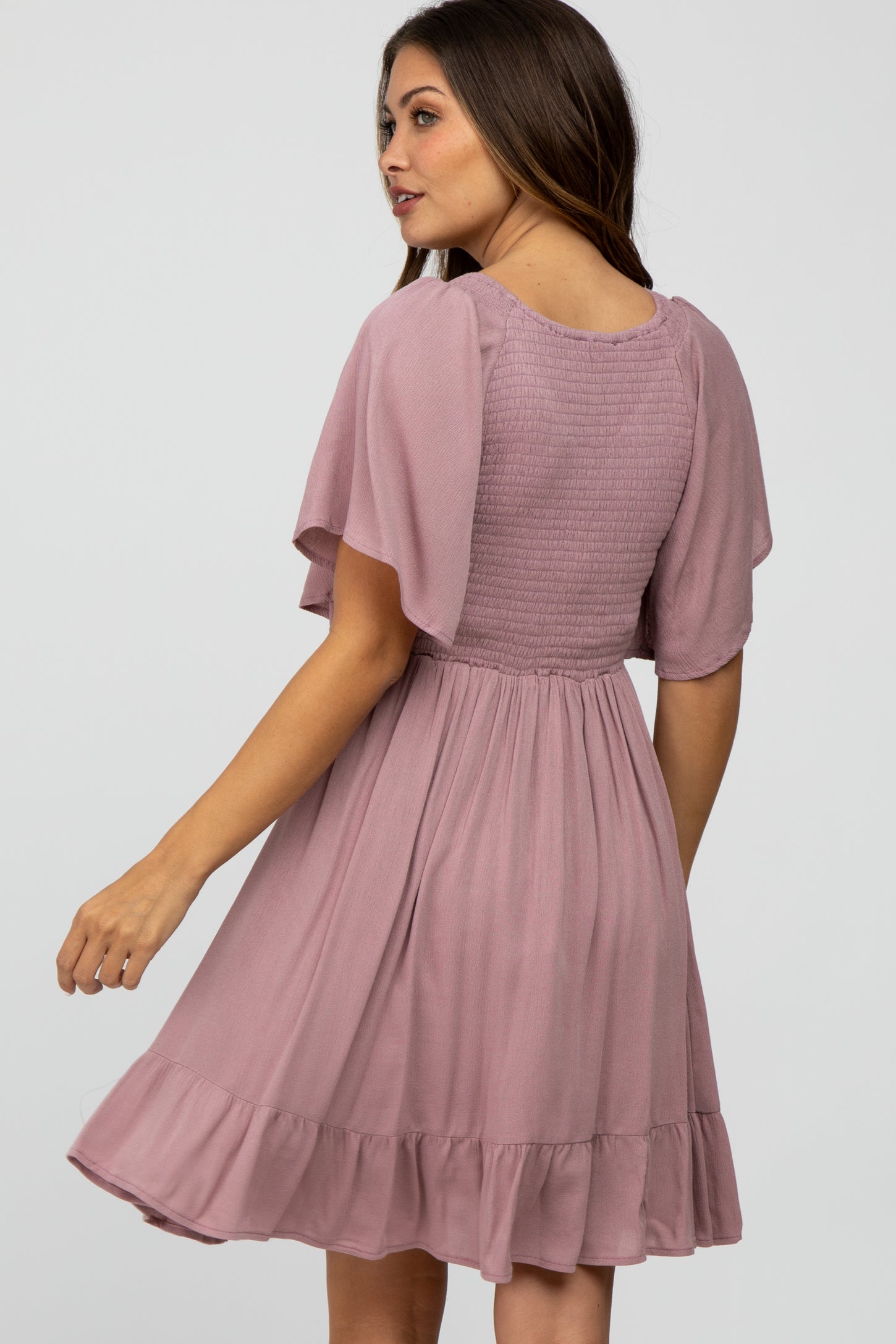 woman wearing a dusty pink maternity dress with short flutter sleeves and a flared skirt.