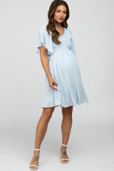 woman wearing a light blue maternity dress with short flutter sleeves and a ruffled hem, showing her baby bump