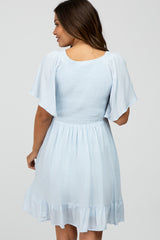 woman wearing a light blue maternity dress with short flutter sleeves and a ruffled hem, showing a relaxed fit