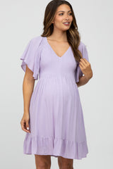 woman wearing a lavender maternity dress with flutter sleeves and a smocked bodice, showing off her baby bump