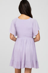 woman wearing a lilac short dress with flutter sleeves and a smocked waist, shown from the back